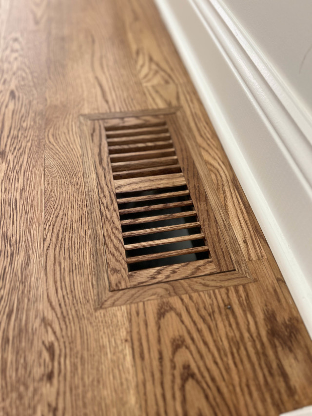 Custom flush-mount vent covers ensure the flooring remains uninterrupted, contributing to the space’s cohesive look.