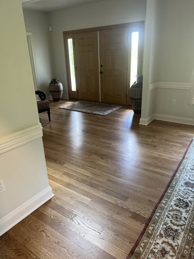 The refinished flooring extends seamlessly into the foyer, creating a cohesive transition from room to room.