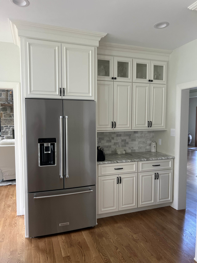 Refrigerator Nook and Glass Cabinets
The built-in refrigerator space ensures a cohesive, clean aesthetic. Glass-front upper cabinets introduce a light, airy element, balancing practicality with display opportunities.