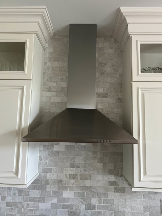 Textured Backsplash and Stainless-Steel Hood
A custom stainless-steel hood replaces traditional cabinetry, creating a modern focal point. The textured tile backsplash complements the design, adding warmth and visual interest to the workspace.