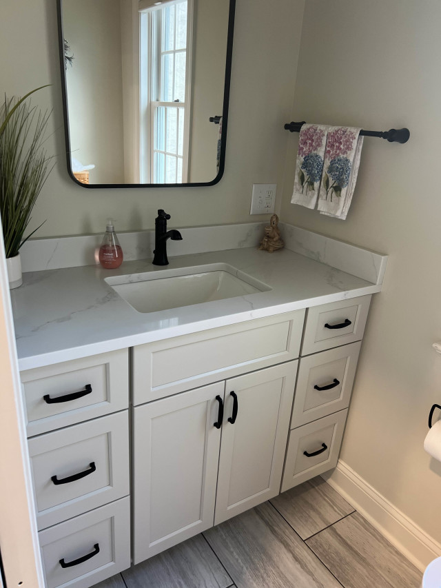 Powder Room Vanity and Mirror
The custom vanity features soft-close drawers and sleek black hardware, paired with a frameless mirror for a modern touch.