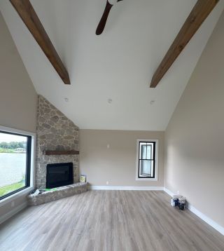 Stone fireplace and exposed wood beams in finished Landenberg lakefront home addition.