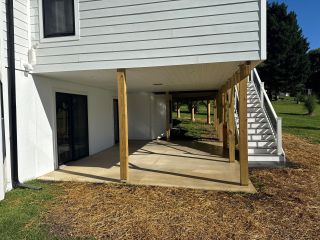 Covered concrete patio beneath an elevated home addition and deck in Landenberg PA.