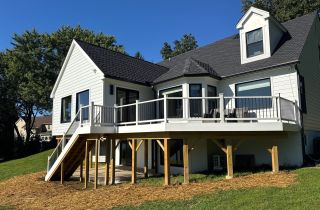 Wide exterior view of finished Landenberg home addition with deck, stairs and black-and-white exterior finishes.